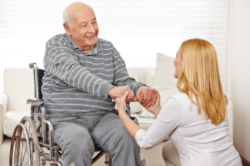 Woman holding the hands of a gentleman in a wheelchair